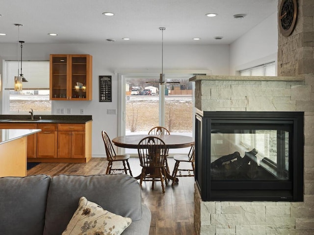 interior space featuring glass insert cabinets, light wood-type flooring, hanging light fixtures, brown cabinetry, and a sink