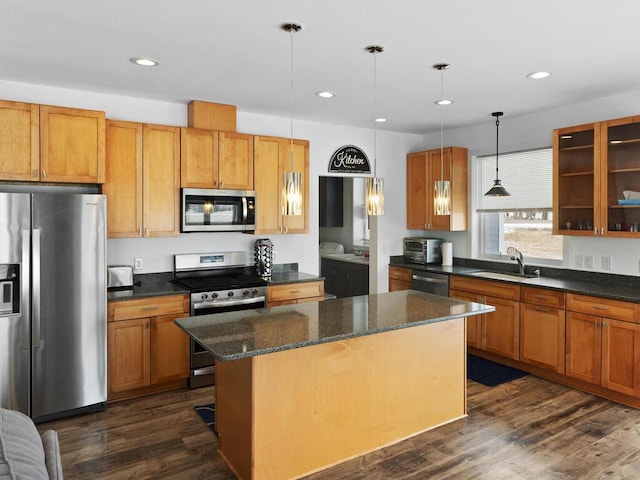 kitchen featuring a kitchen island, glass insert cabinets, dark wood-type flooring, stainless steel appliances, and a sink