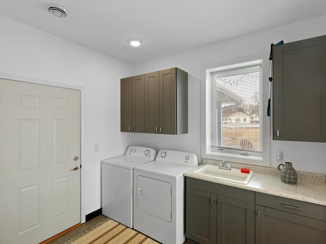 laundry room with visible vents, light wood-type flooring, washer and dryer, a sink, and cabinet space