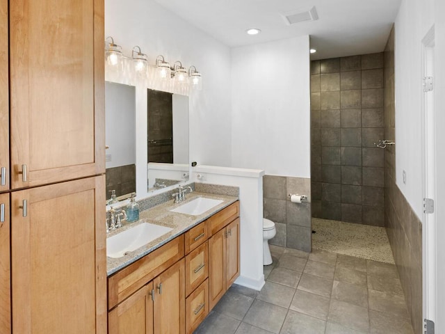 full bathroom with a sink, toilet, tile walls, and tile patterned floors