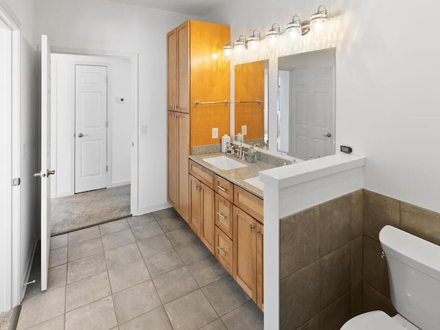 bathroom featuring double vanity, tile patterned floors, toilet, and a sink