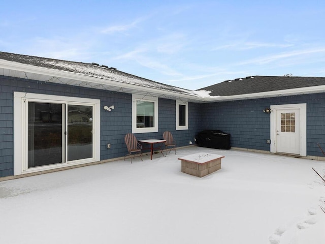 snow covered rear of property with a patio area and an outdoor fire pit