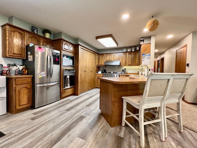 kitchen featuring stainless steel fridge, a breakfast bar, kitchen peninsula, built in microwave, and oven