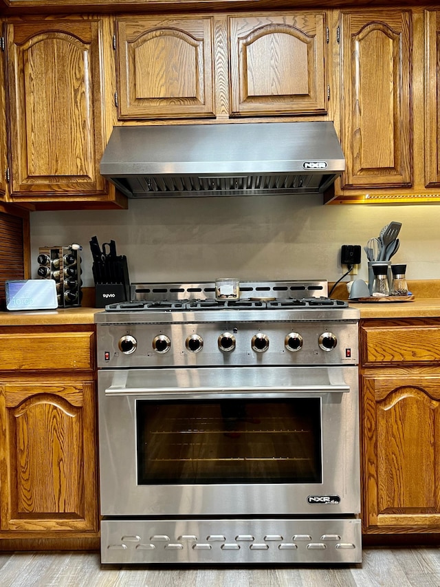 kitchen with high end stove and wall chimney exhaust hood