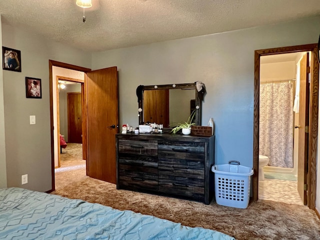 carpeted bedroom with connected bathroom and a textured ceiling