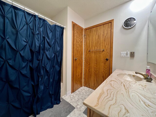 bathroom featuring vanity, shower / tub combo with curtain, and a textured ceiling