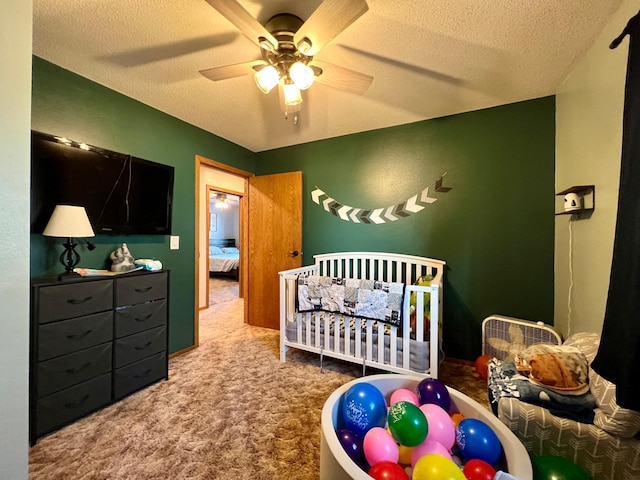 carpeted bedroom with a nursery area, ceiling fan, and a textured ceiling