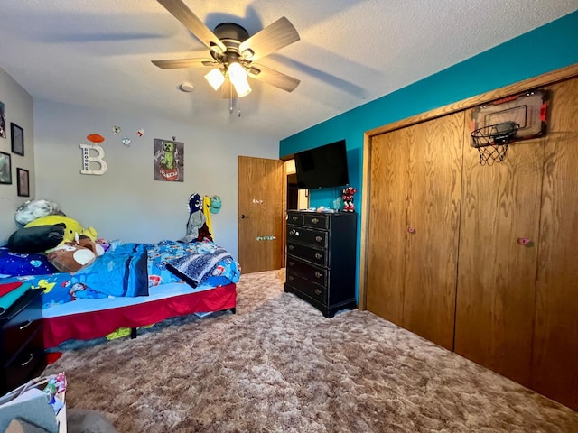 bedroom with ceiling fan, carpet floors, a closet, and a textured ceiling