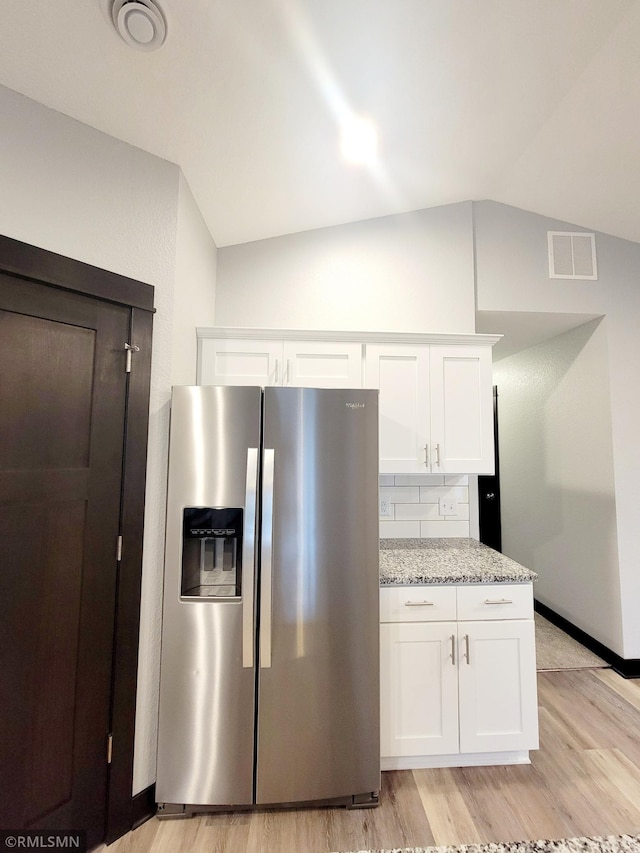 kitchen with white cabinetry, lofted ceiling, and stainless steel fridge