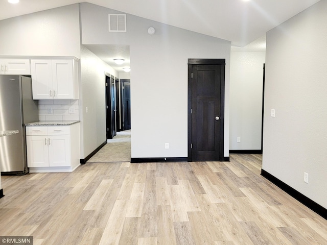 spare room with light hardwood / wood-style flooring and vaulted ceiling