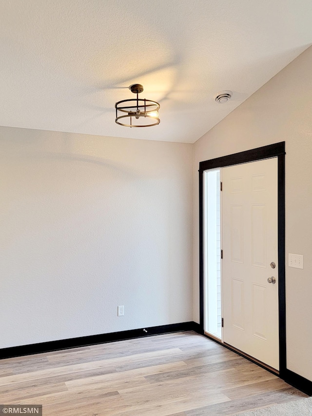 foyer entrance with lofted ceiling and light hardwood / wood-style floors