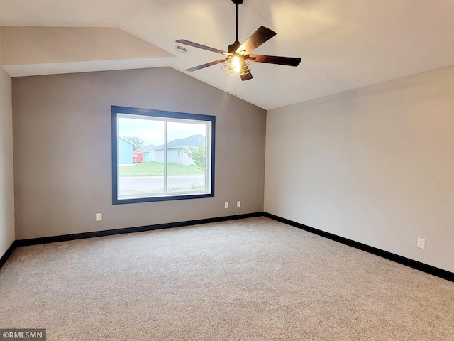 carpeted spare room featuring vaulted ceiling and ceiling fan