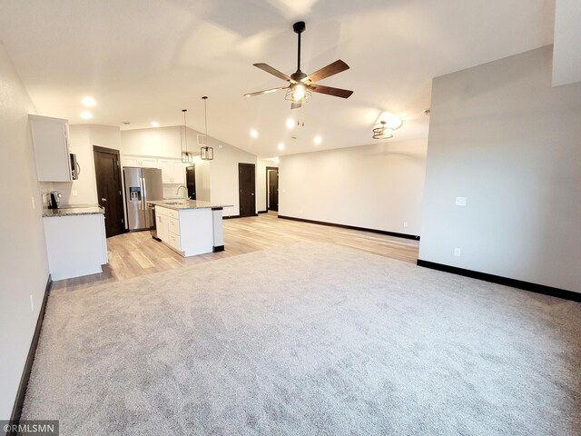 unfurnished living room with sink, vaulted ceiling, and ceiling fan