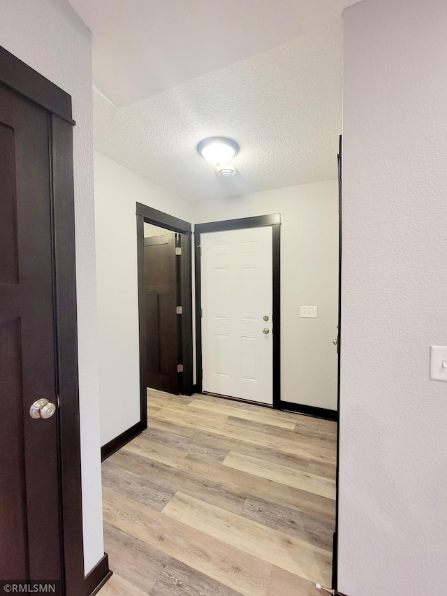 hallway featuring a textured ceiling and light hardwood / wood-style flooring