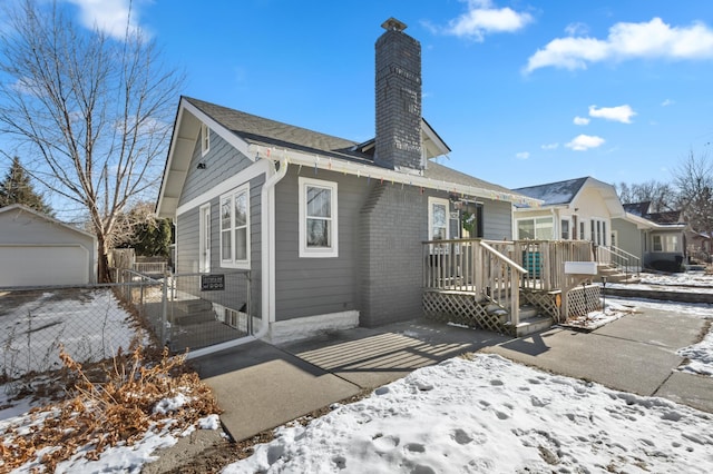 snow covered back of property featuring a garage and an outdoor structure