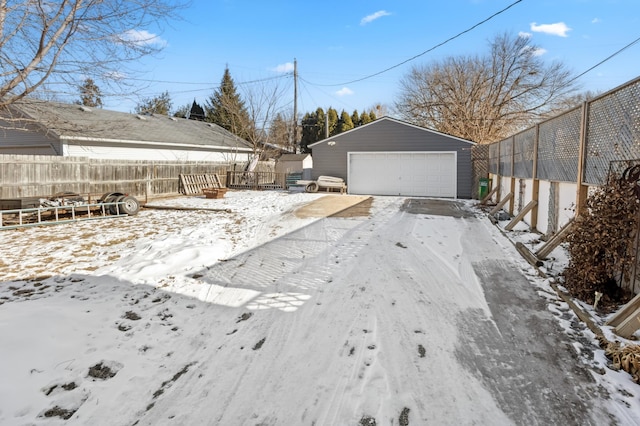 yard layered in snow featuring an outbuilding and a garage