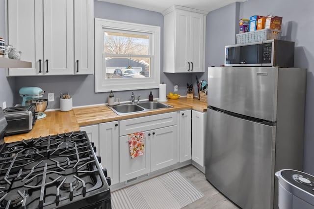 kitchen featuring white cabinetry, appliances with stainless steel finishes, sink, and light hardwood / wood-style flooring