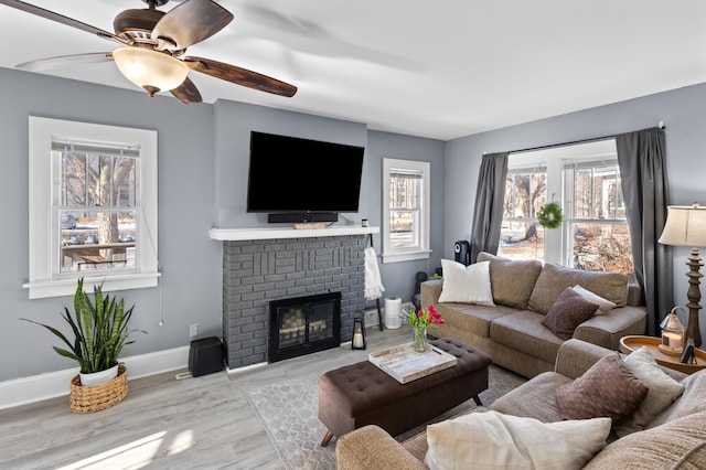 living room featuring ceiling fan, a fireplace, and light hardwood / wood-style floors