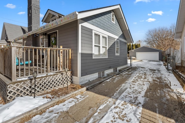 snow covered property featuring a garage and an outdoor structure