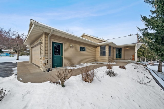 snow covered rear of property featuring a garage