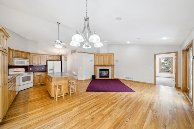 kitchen featuring lofted ceiling, a center island, light wood-type flooring, white appliances, and decorative backsplash