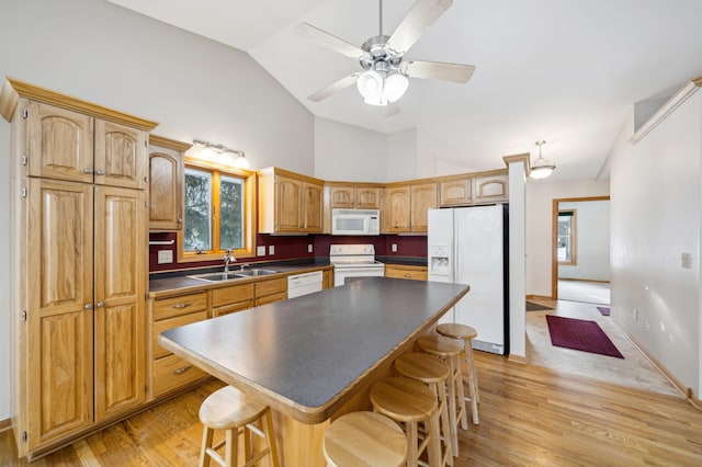 kitchen with a breakfast bar, sink, a center island, white appliances, and light hardwood / wood-style flooring