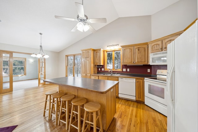 kitchen with sink, white appliances, a center island, light hardwood / wood-style floors, and french doors