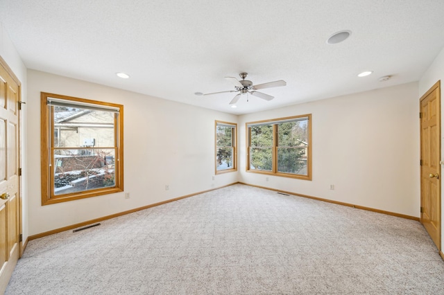 carpeted empty room with a textured ceiling, plenty of natural light, and ceiling fan