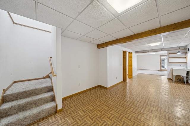 basement featuring parquet floors and a paneled ceiling