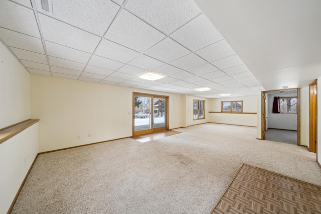 basement with a paneled ceiling and carpet