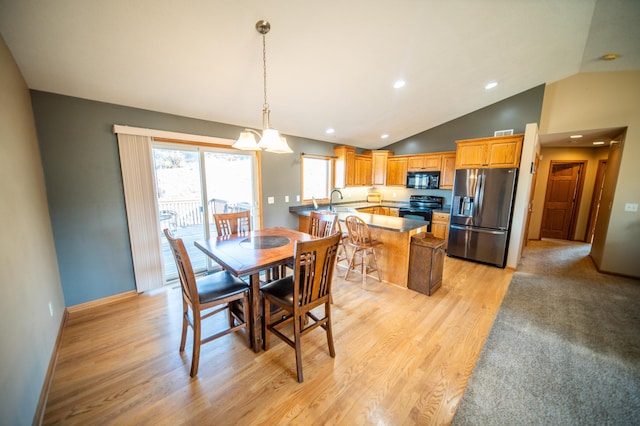 dining room with vaulted ceiling, sink, an inviting chandelier, and light wood-type flooring