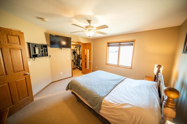 carpeted bedroom featuring a textured ceiling, a walk in closet, a closet, and ceiling fan