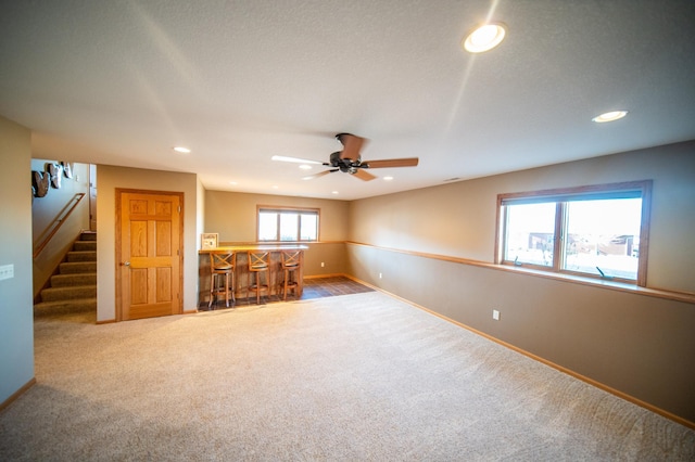 carpeted empty room featuring ceiling fan and indoor bar