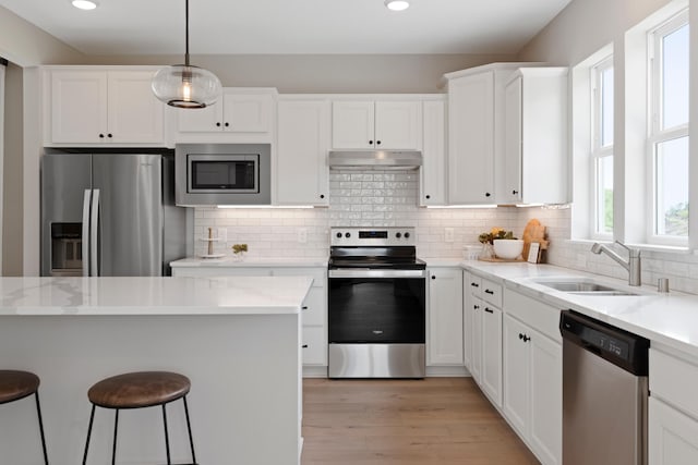 kitchen featuring sink, decorative light fixtures, appliances with stainless steel finishes, light stone countertops, and white cabinets