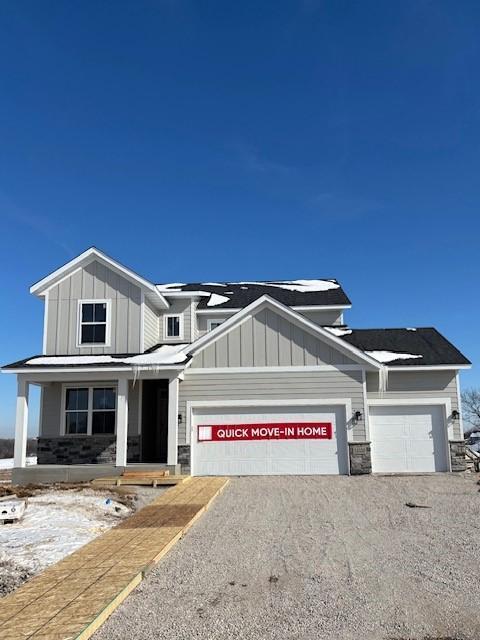 view of front facade featuring a garage, stone siding, gravel driveway, covered porch, and board and batten siding