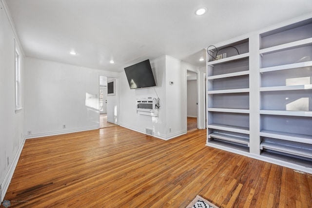 unfurnished living room featuring wood-type flooring and built in features