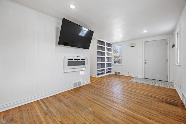 unfurnished living room with hardwood / wood-style floors and heating unit