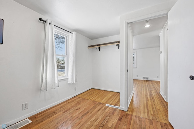 walk in closet featuring a barn door and light hardwood / wood-style floors