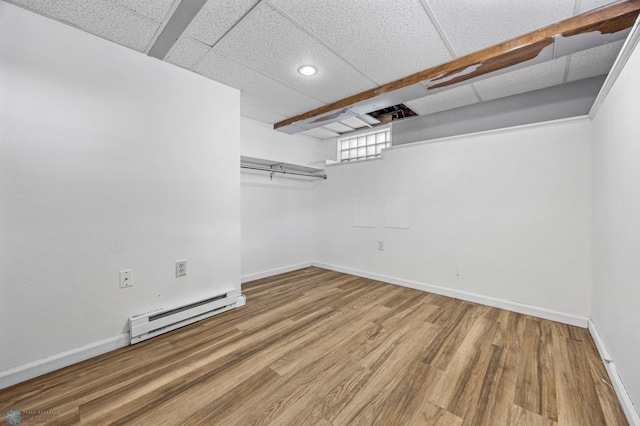 spacious closet featuring wood-type flooring, a baseboard heating unit, and a drop ceiling