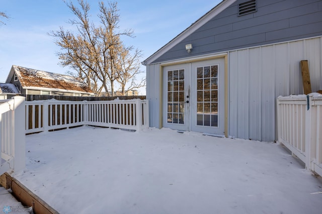 snow covered deck featuring french doors