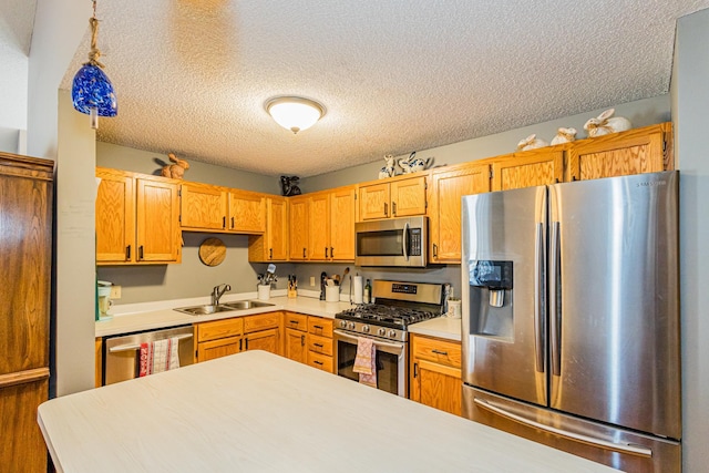 kitchen with stainless steel appliances, decorative light fixtures, sink, and a textured ceiling