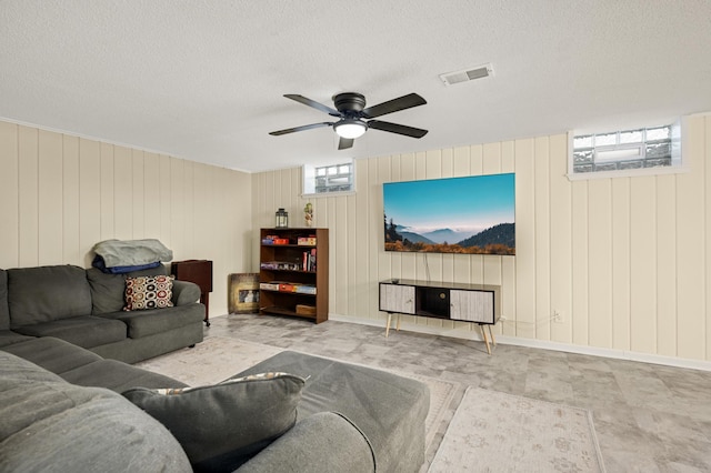 living area with a ceiling fan, visible vents, and a textured ceiling