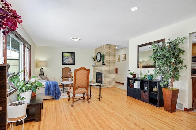 sitting room with baseboards, a fireplace, visible vents, and wood finished floors