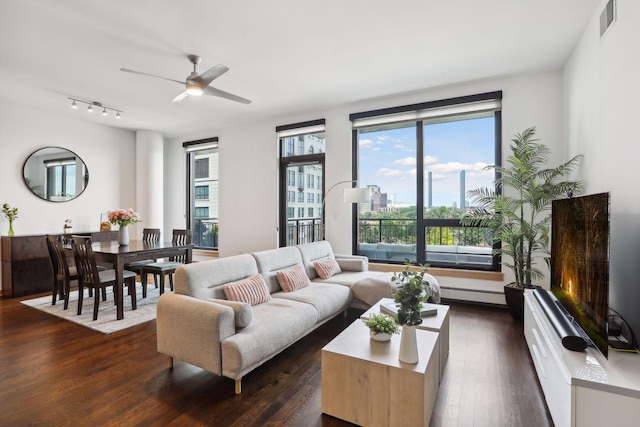 living room featuring ceiling fan, plenty of natural light, dark hardwood / wood-style floors, and a baseboard radiator