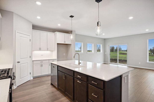 kitchen featuring sink, white cabinetry, hanging light fixtures, appliances with stainless steel finishes, and an island with sink