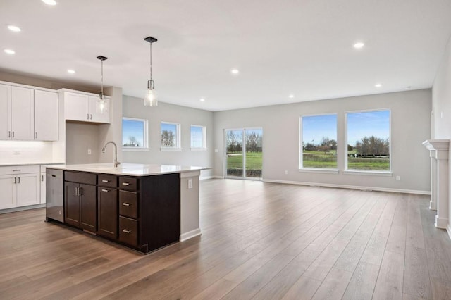 kitchen featuring recessed lighting, light countertops, light wood-style floors, white cabinetry, and a sink