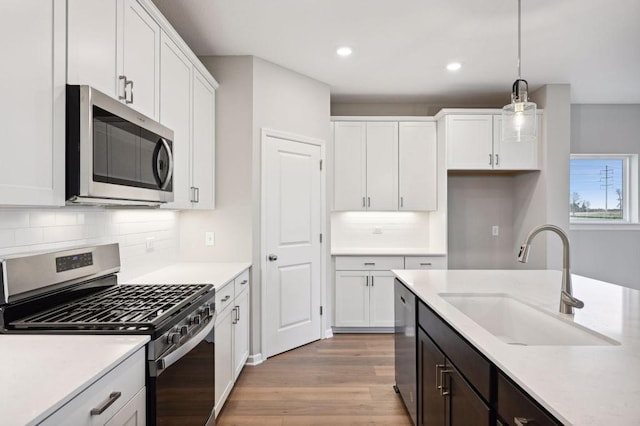 kitchen featuring stainless steel appliances, light countertops, a sink, and white cabinetry