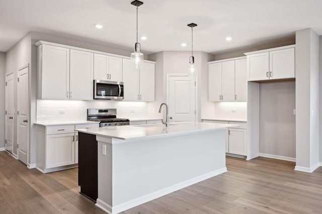 kitchen with stainless steel appliances, a sink, light wood-style floors, white cabinets, and light countertops