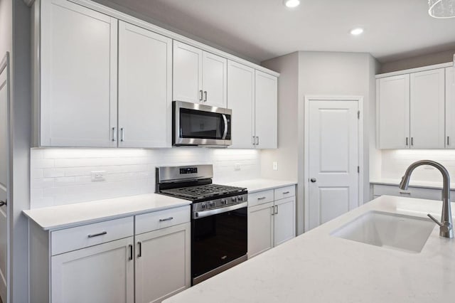 kitchen featuring white cabinetry, decorative backsplash, stainless steel appliances, and a sink