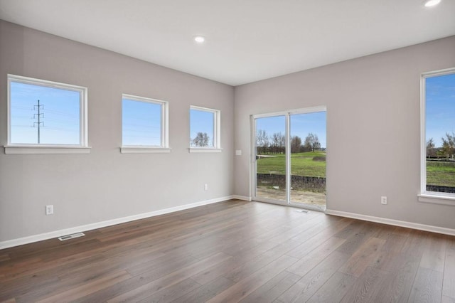 empty room featuring recessed lighting, dark wood-style flooring, visible vents, and baseboards